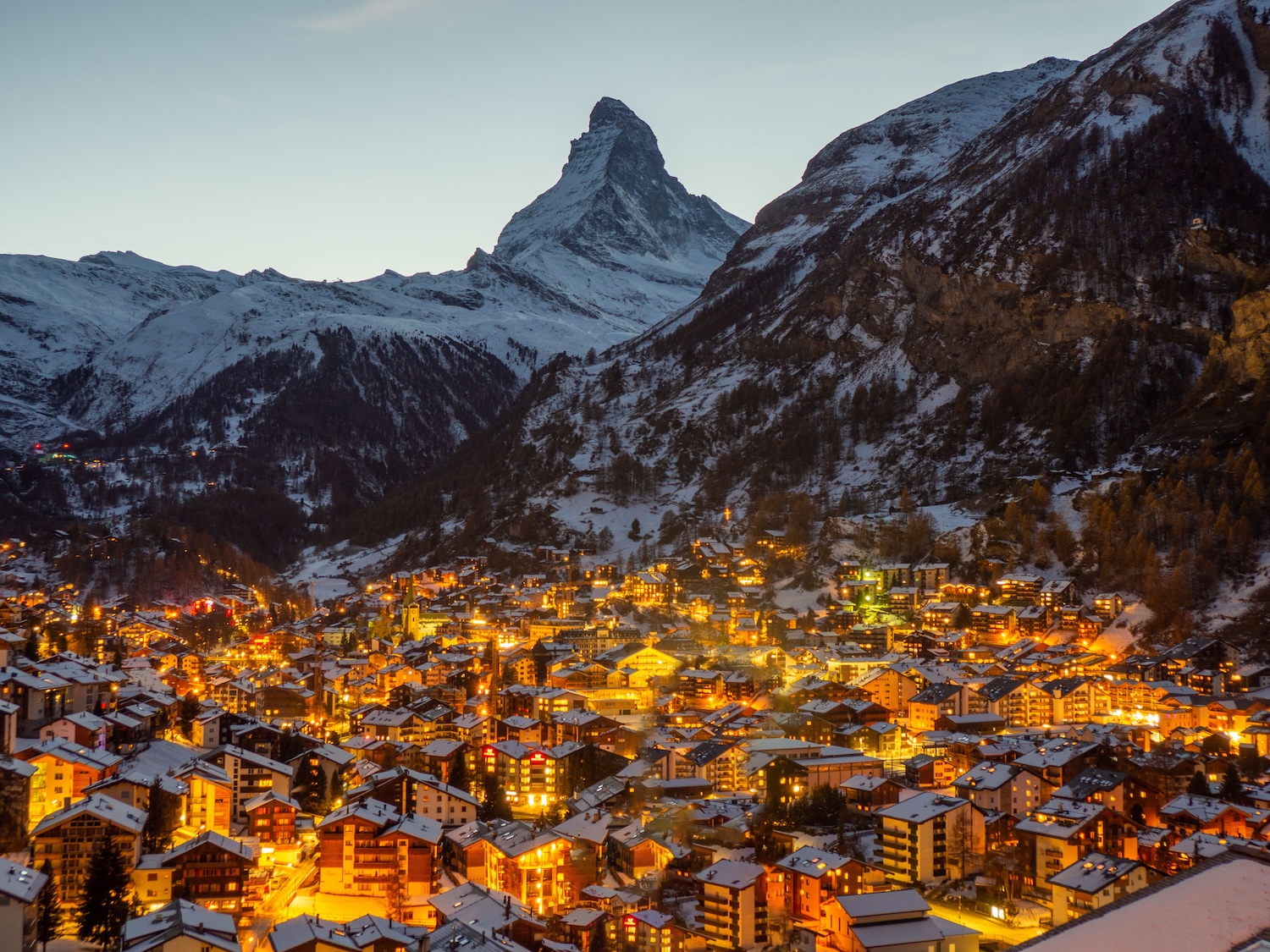 a town in the night with snow on the ground and the mountain range in the