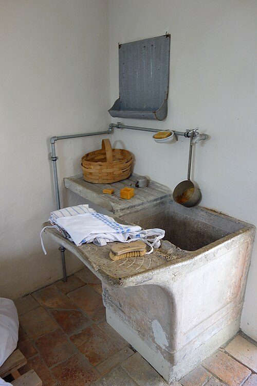 Historic stone wash basin with a washboard and a wooden bucket at the Ballenberg open-air museum