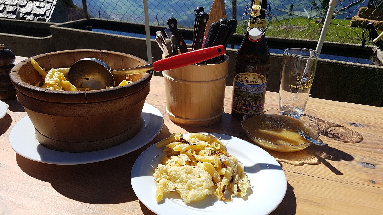Traditional Swiss food: Älplermagronen served from a wooden bowl on the terrace of an alp hut