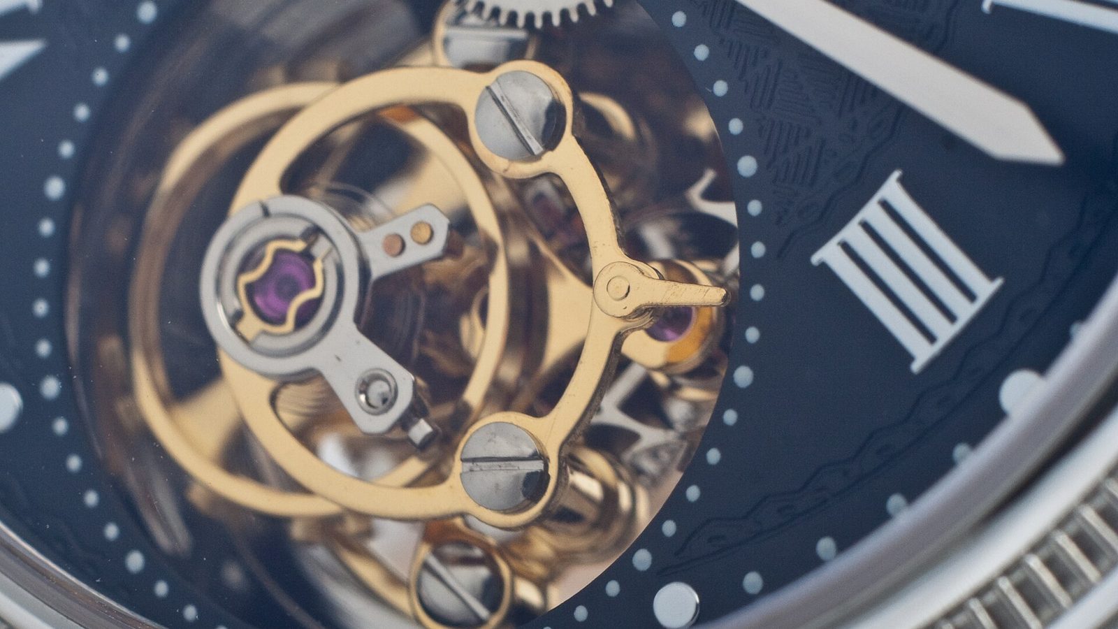 Why are Swiss watches so expensive: close-up of a tourbillon cage turning inside a mechanical watch dial